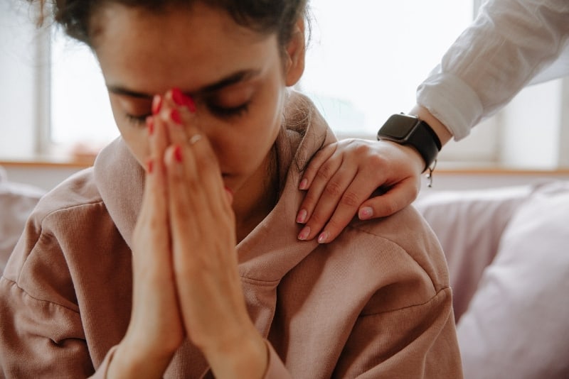 mujer con reloj negro consolando a mujer