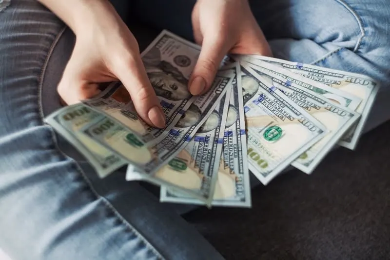 woman counting money near her lap wearing jeans