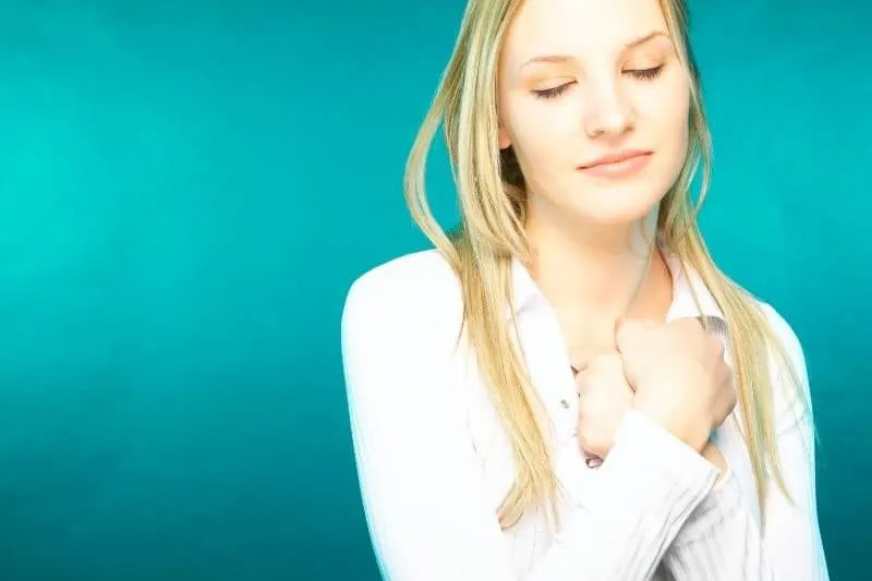 woman day dreaming closing her eyes with fist put close to her heart