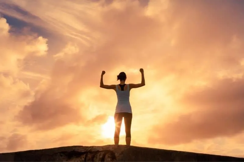 woman flexing her muscles against the sunset 