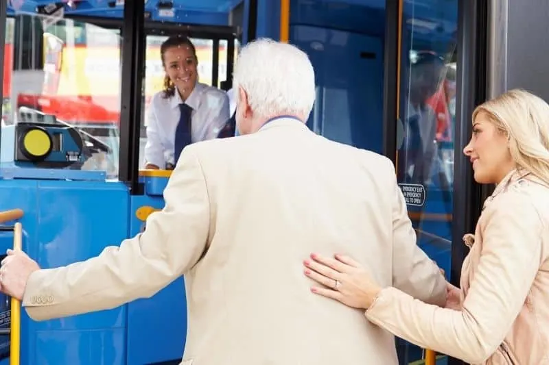 woman helping senior man getting in a public transportation