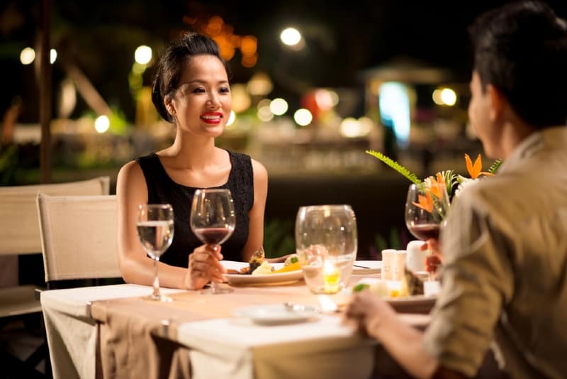 woman holding glass of wine while looking at man