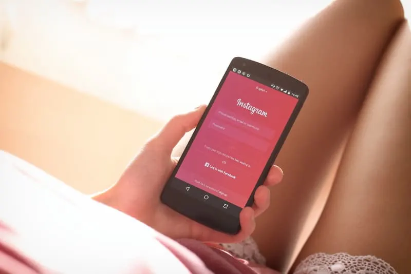 woman holding black phone with instagram app on screen