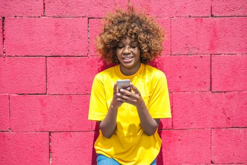 woman in yellow t-shirt holding smartphone