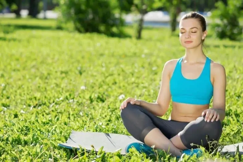 woman in park meditating wearing athletic wear