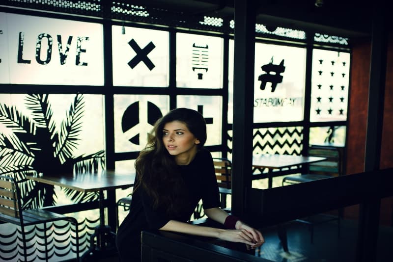 woman in black top leaning on desk