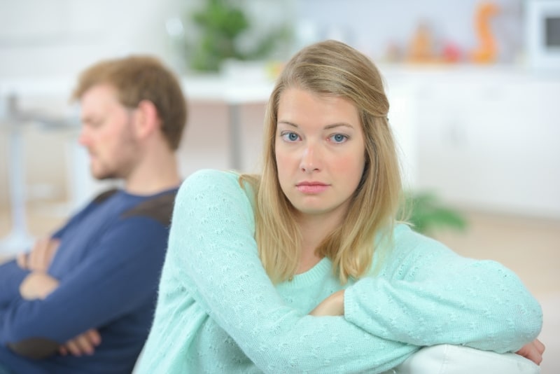 mujer rubia con top verde apoyada en un sofá