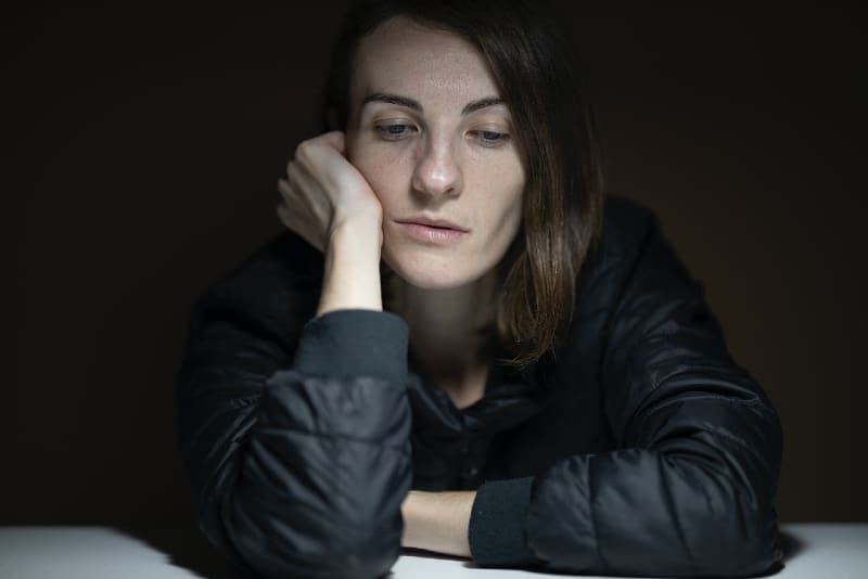 sad woman in black jacket leaning on table