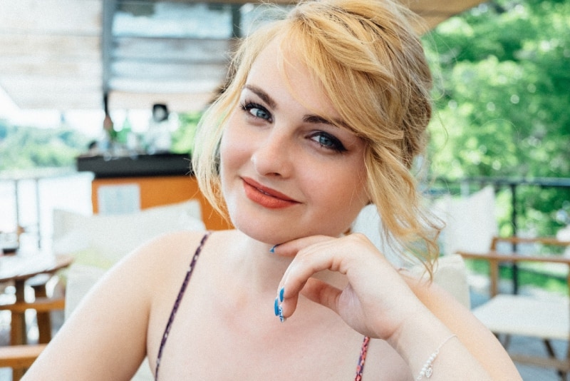 blonde woman with blue eyes leaning on table