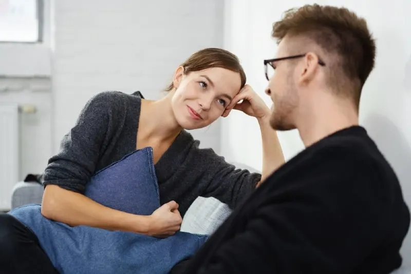 smiling woman holding blue pillow while looking at man
