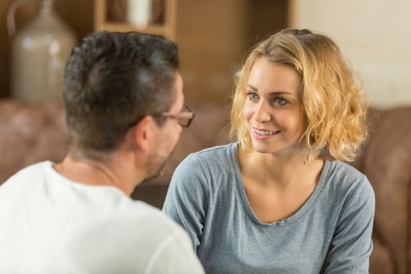 mulher sorridente a olhar para um homem sentado num espaço interior