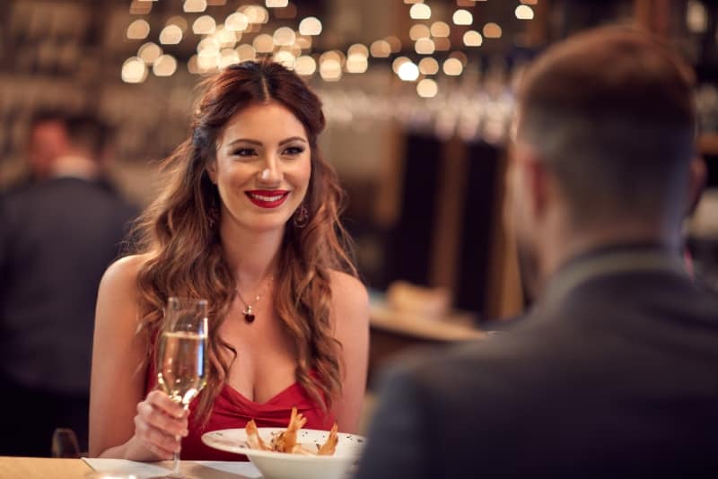 donna sorridente che guarda un uomo con in mano un bicchiere di champagne