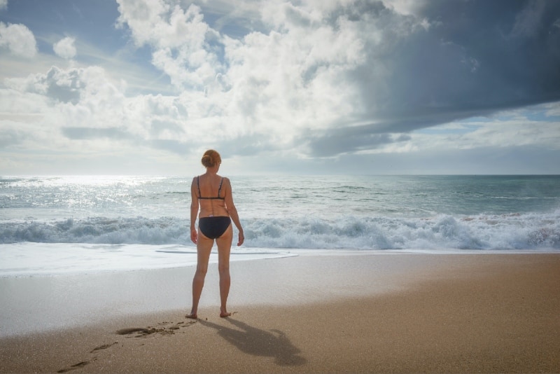 woman standing on seashore looking at ocean