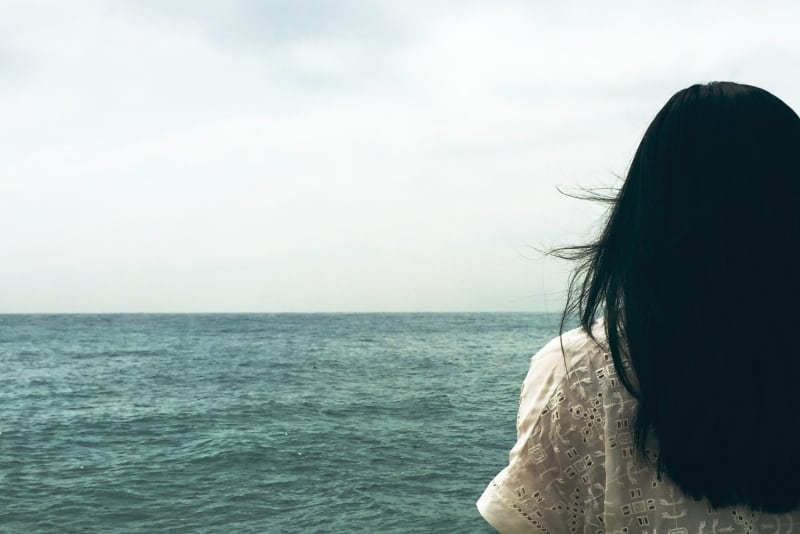 woman in white top looking at sea