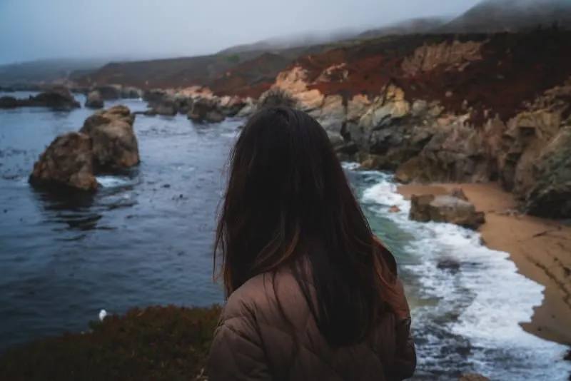 woman in brown jacket looking at sea