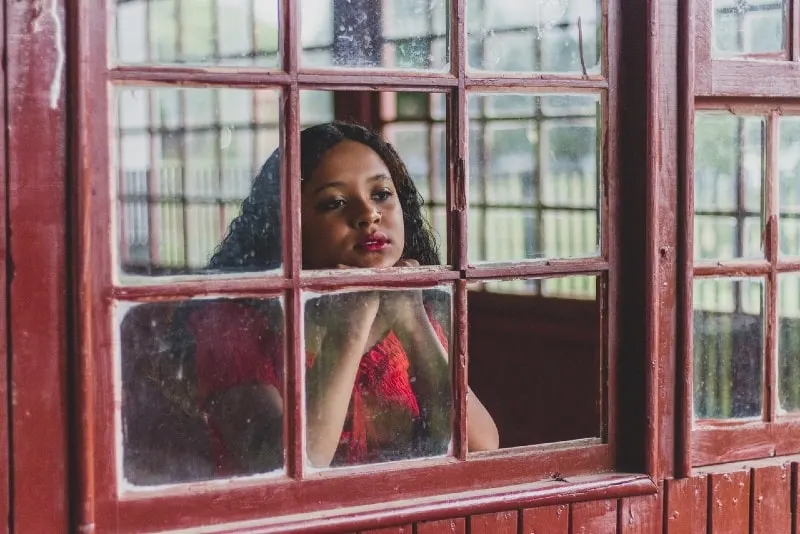 woman in red top looking through window