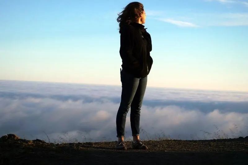 woman looking behind the cloudy space behind the mountain she is standing