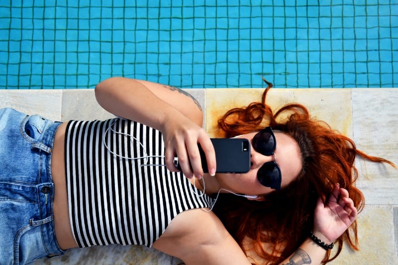 woman with sunglasses lying on floor near pool