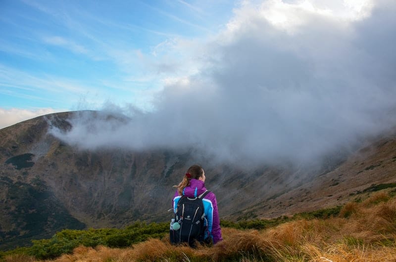 mujer en la cima de una montaña mirando la espesa niebla