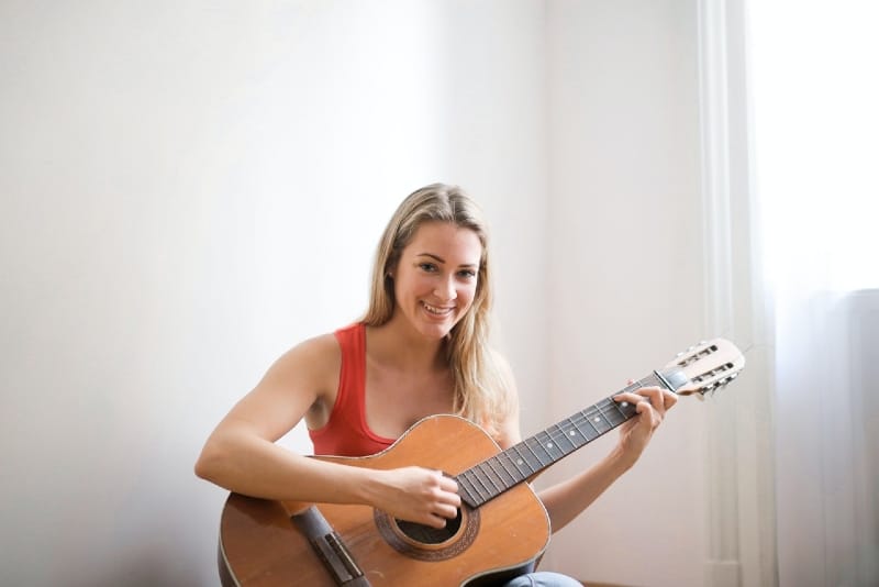 mujer con top rojo tocando la guitarra