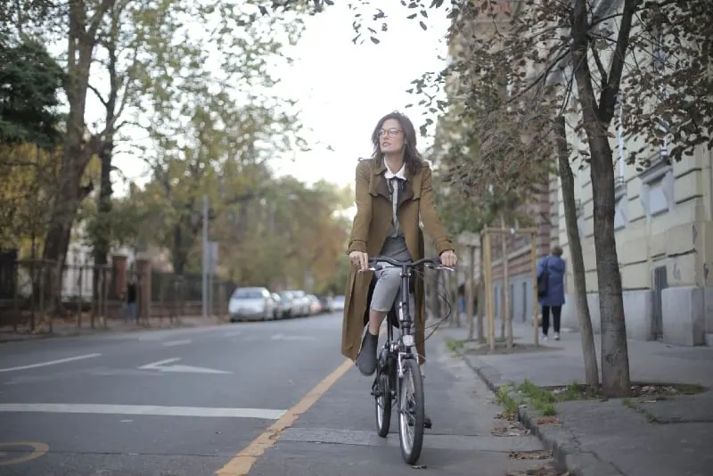 woman in brown coat riding a bicycle