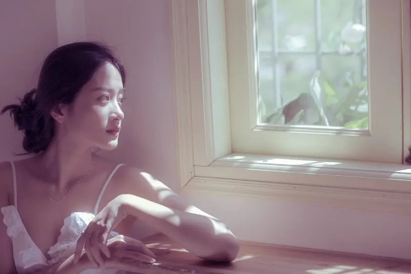 woman sitting at table looking at window