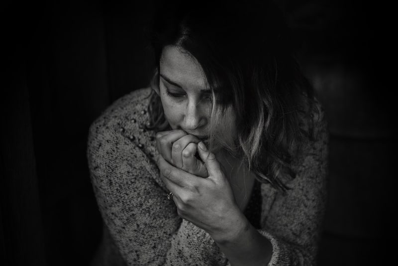 mujer triste con jersey gris sentada en interior