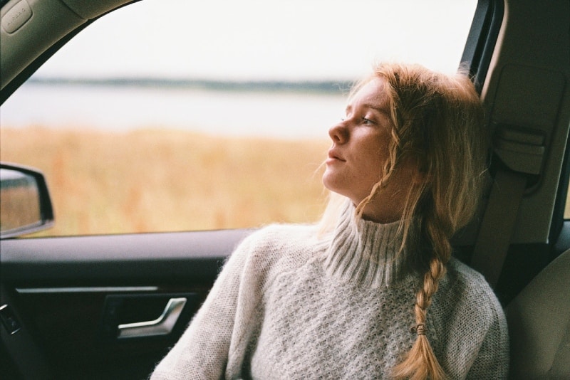 blonde woman in gray sweater sitting inside car