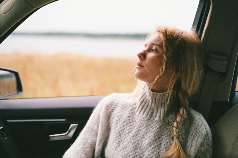 donna bionda con maglione grigio seduta in auto