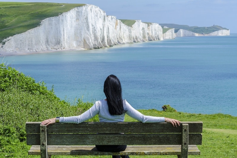 woman sitting on bench looking at sea