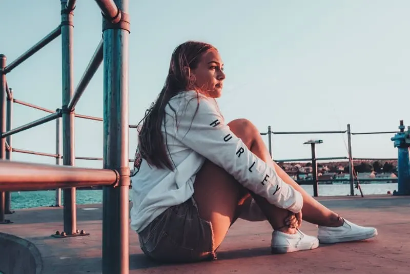 woman in white sweatshirt sitting on ground