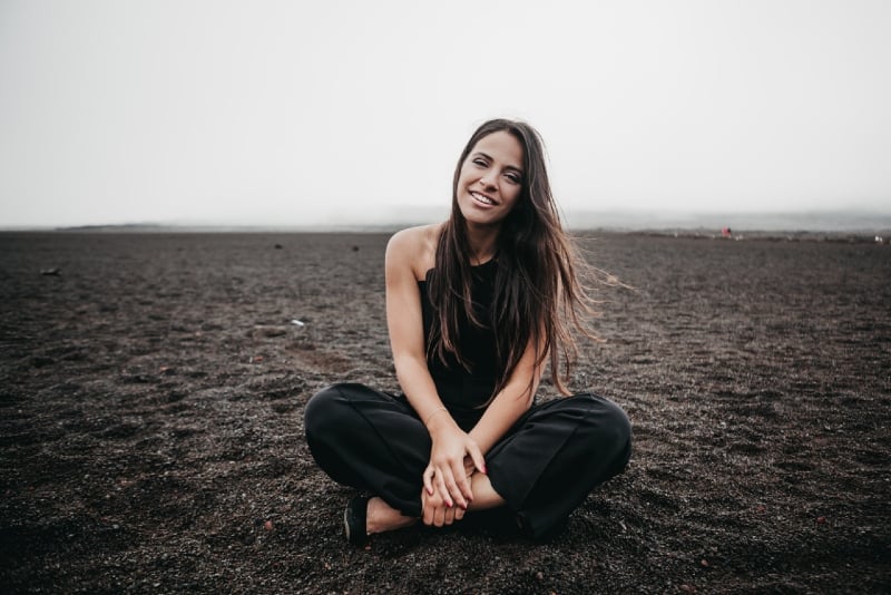 mulher sorridente de top preto sentada no chão