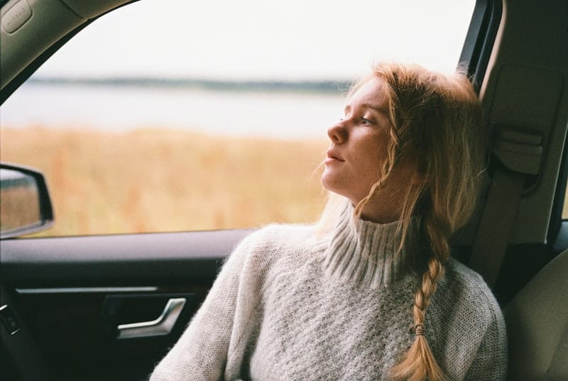 mujer sentada en el asiento del pasajero del coche pensando profundamente 