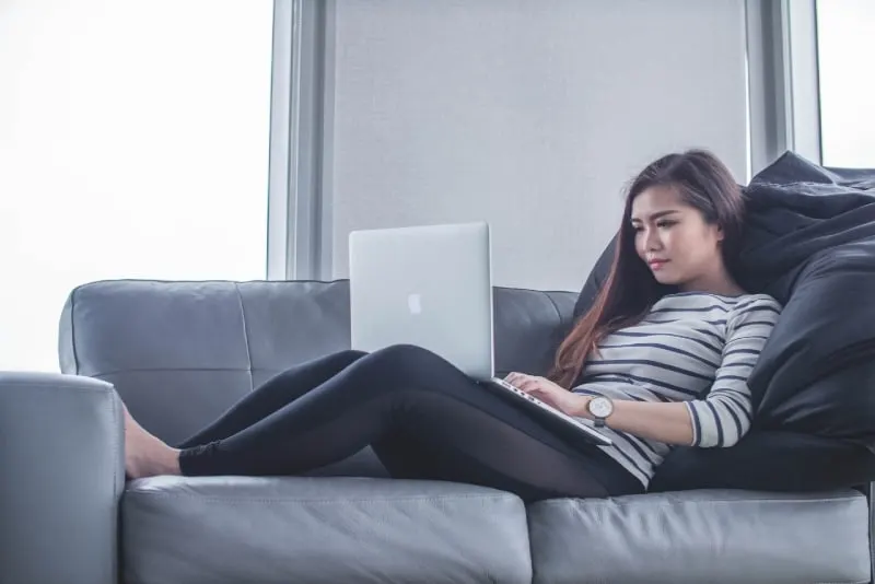 woman sitting on sofa while using laptop