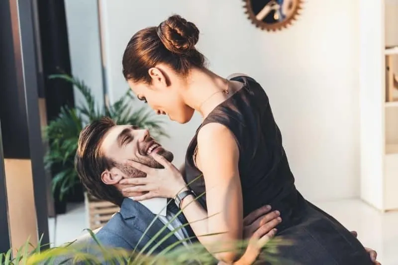 woman sitting on the lap of the man holding her waist inside living room