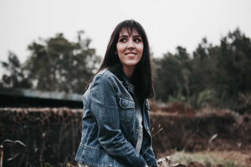 mulher sorridente com casaco de ganga azul sentada ao ar livre