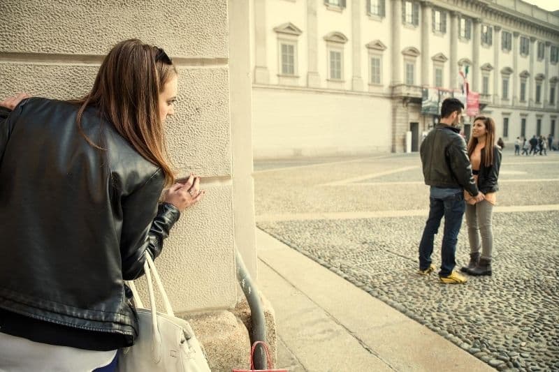 woman stalking on his man seeing another woman outside a big building