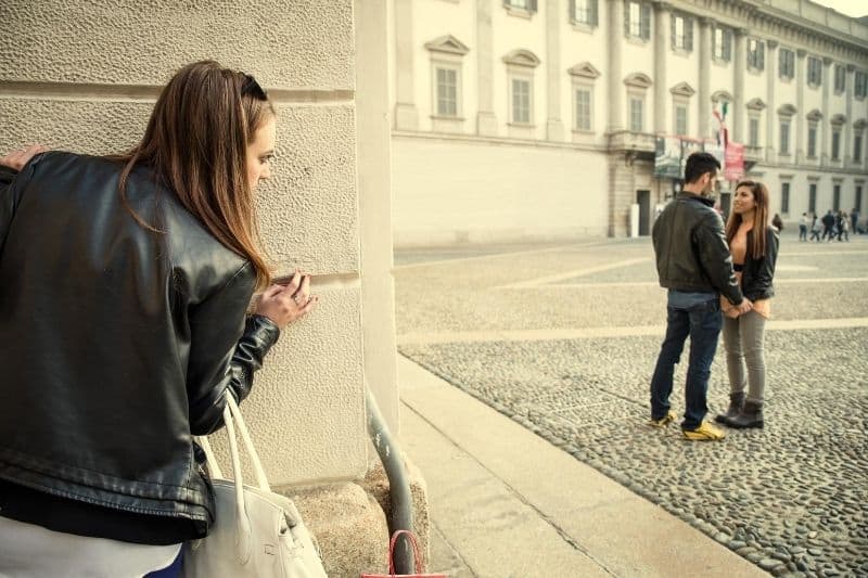 donna che pedina il suo uomo che vede un'altra donna fuori da un grande edificio