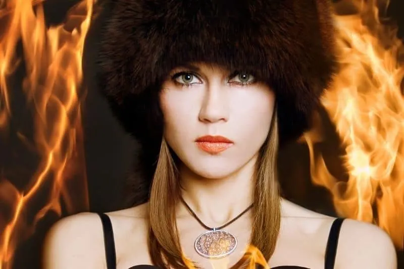 woman standing around with fire wearing a thick fur headcap