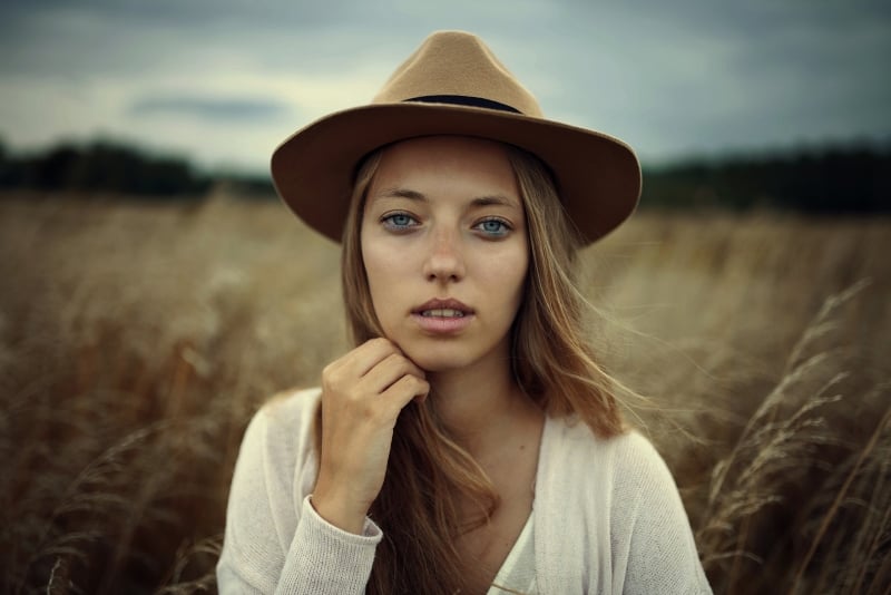 woman with hat standing in field