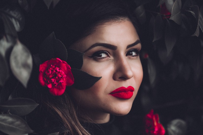 woman with pink lipstick standing near plant