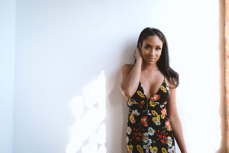 woman in black floral dress standing near wall