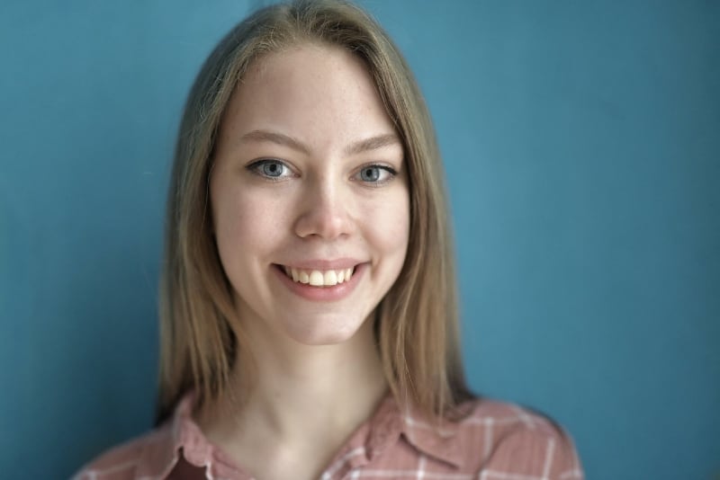 smiling woman standing near blue wall