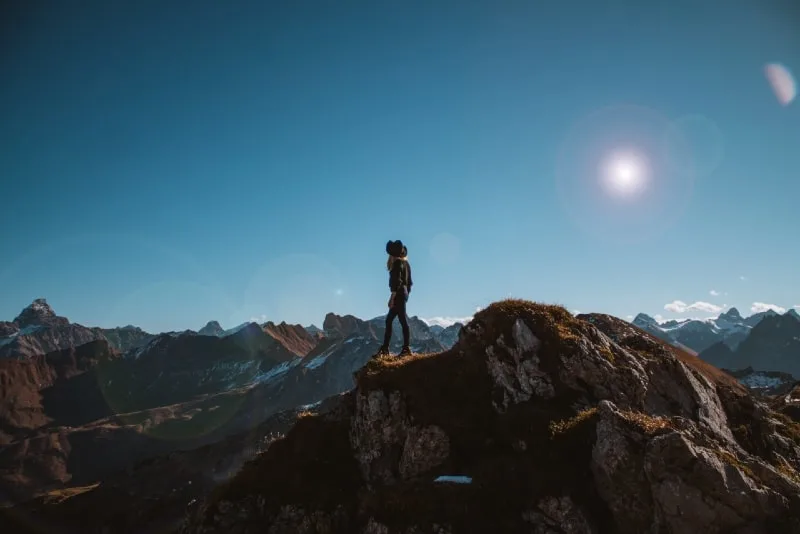 woman with black hat standing on cliff