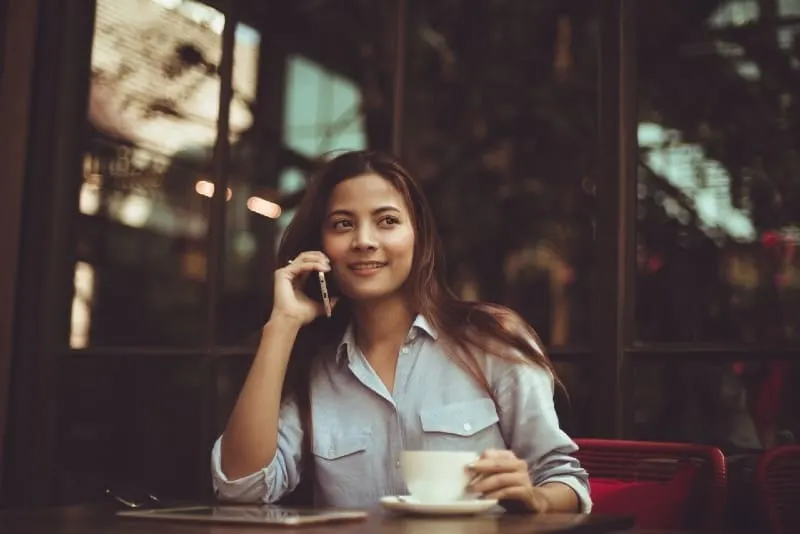 woman talking on phone while sitting at table