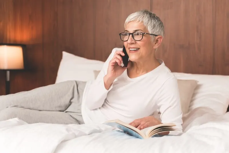 woman talking on the phone while sitting on bed