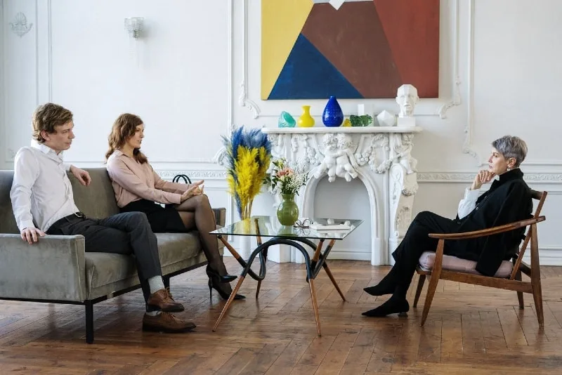 woman talking to therapist while sitting on sofa near man