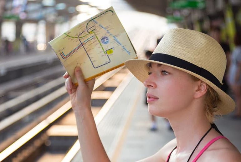 mujer viajera trayendo un mapa en una estación de tren