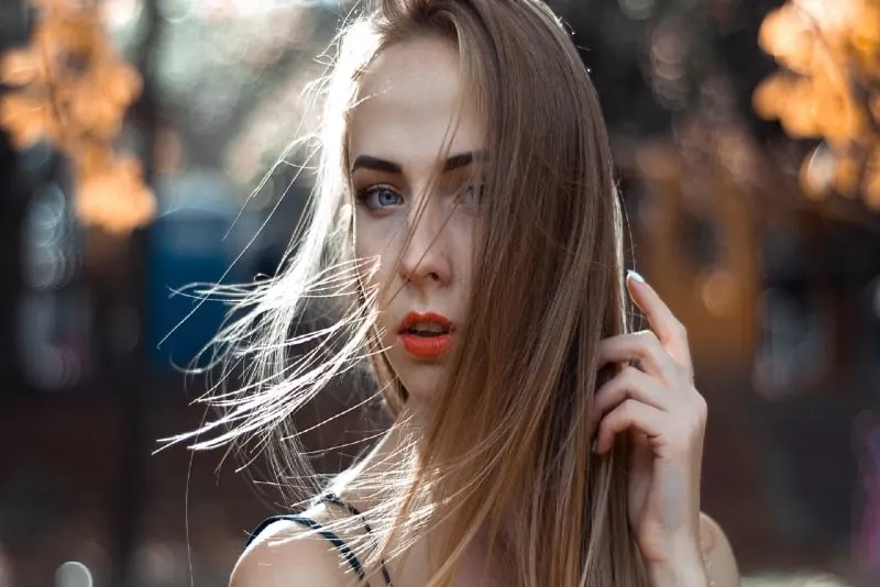 woman with orange lipstick touching her hair