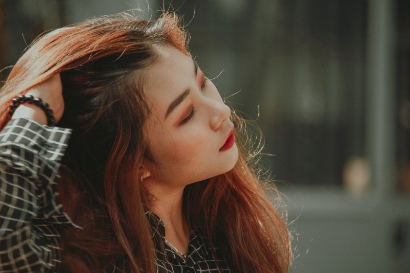 mujer tocándose el pelo de pie al aire libre